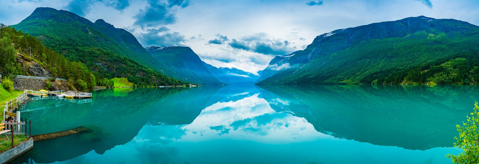 Calm turquoise Norwegian fjord between steep green mountains