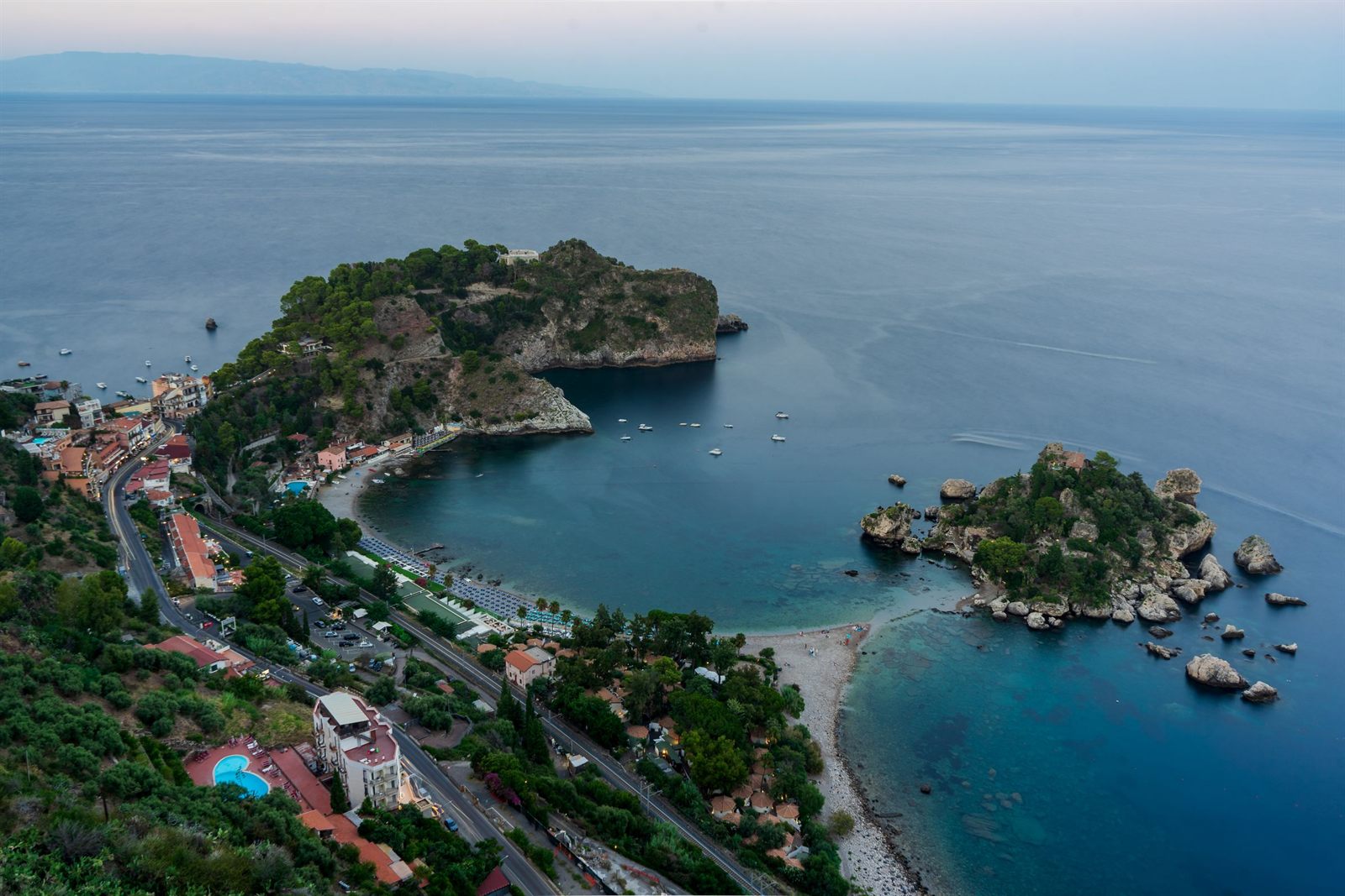 Aerial view of a curving Sicilian bay and a small island off Taormina